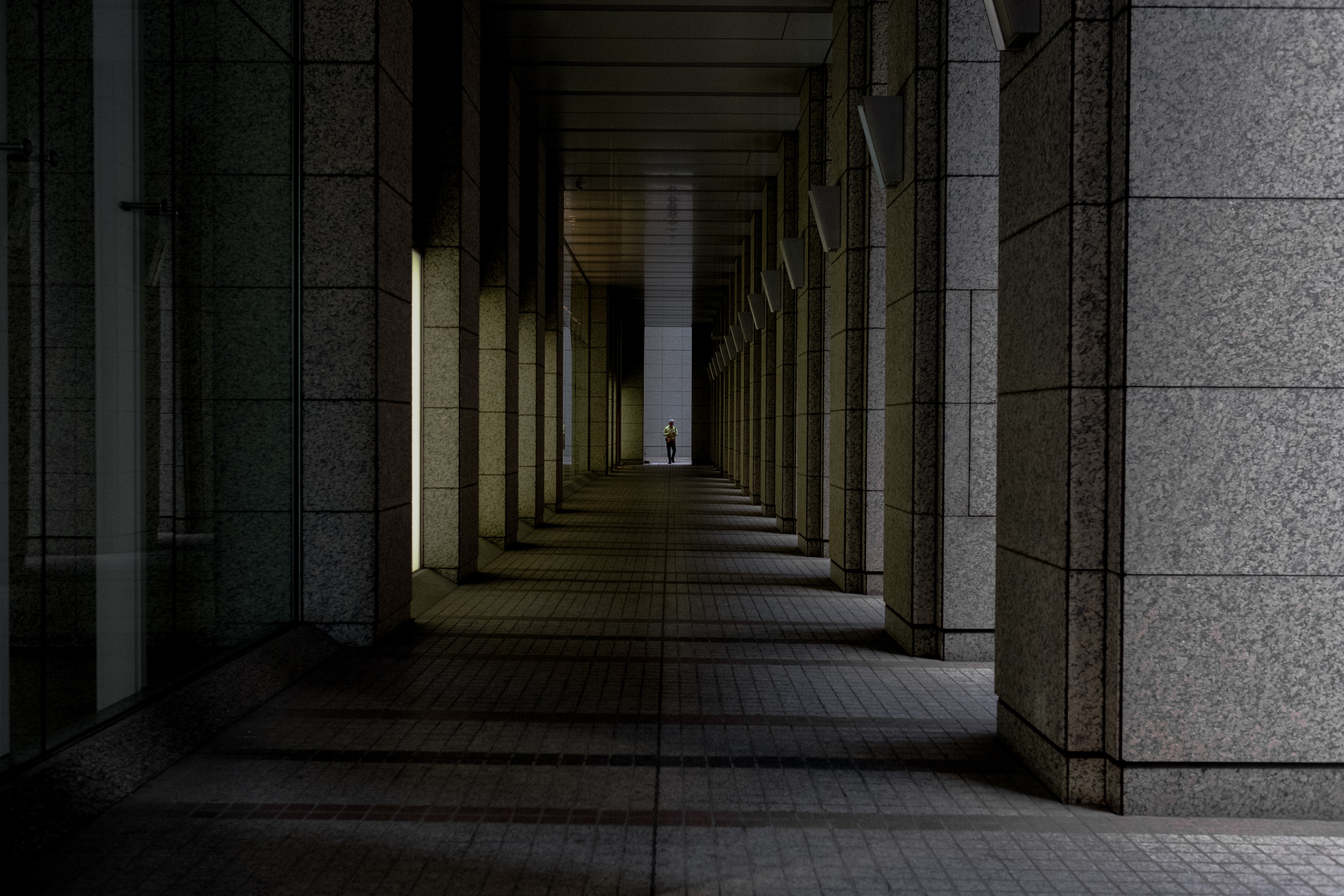 man walking at the end of path between stone columns